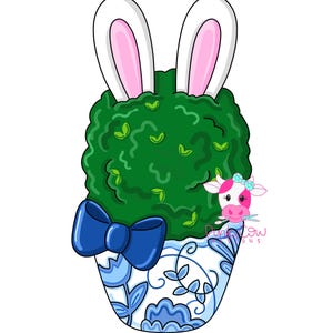 May include: A green bush with bunny ears sticking out of the top, in a blue and white patterned planter with a blue bow. The planter has a pink cow peeking out from behind it with the text "Pink Cow Designs".