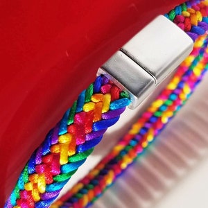 May include: A rainbow colored braided bracelet with a silver magnetic clasp.