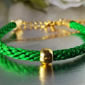 St. Patrick&#39;s Day Shamrock Green Bracelet: Hand-Woven in Green Satin Thread with a Round Gold-Plated Accent Bead and Adjustable Clasp.