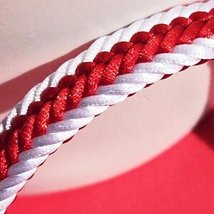 May include: A red and white braided bracelet with a silver magnetic clasp.