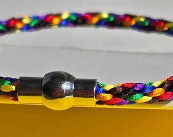 May include: A multi-colored braided bracelet with a silver magnetic clasp. The bracelet is made of rainbow colored cords.