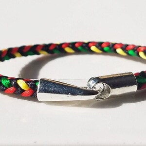 May include: A braided bracelet with red, yellow, green, and black threads. The bracelet has a silver clasp.