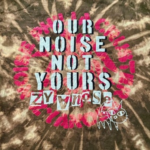 May include: A brown and white tie-dye t-shirt with the text "OUR NOISE NOT YOURS" in a circle with a pink and red design. A cartoon cat is in the bottom right corner.