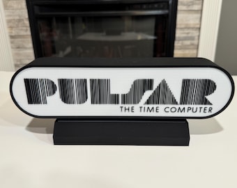 以下が含まれることがあります： レトロなフォントスタイルで「PULSAR THE TIME COMPUTER」というテキストが書かれた白黒の看板です。