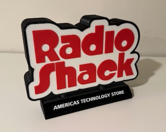 May include: A black and white sign with the red text "Radio Shack" and the tagline "America's Technology Store".