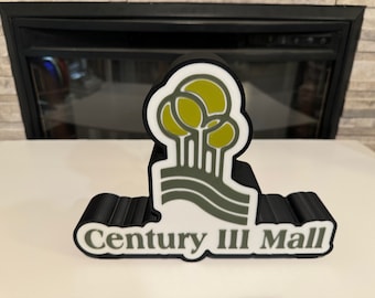 以下が含まれることがあります： 「Century III Mall」という文字と緑色のスタイリッシュな木のロゴが書かれた、黒と白の3Dプリントされた看板です。