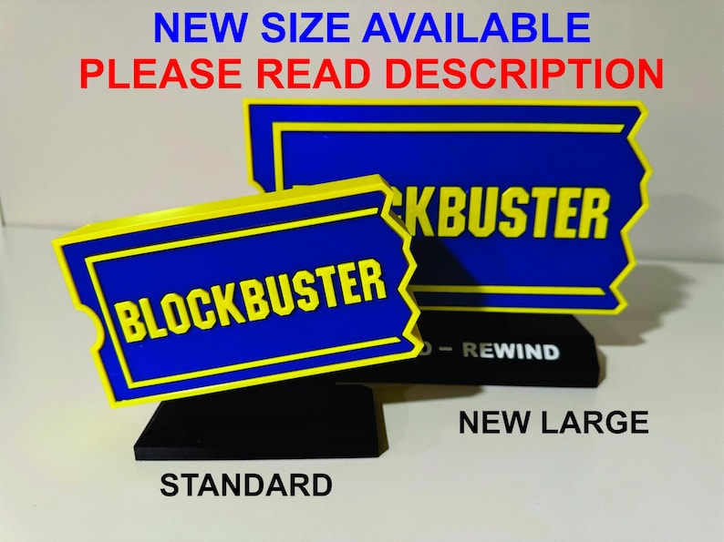 以下が含まれることがあります： 「STANDARD」と「NEW LARGE」のラベルが付いた、2つのBlockbusterビデオレンタル店の看板。両方の看板は青色で黄色の縁取りがあり、黄色い文字で「BLOCKBUSTER」と書かれています。