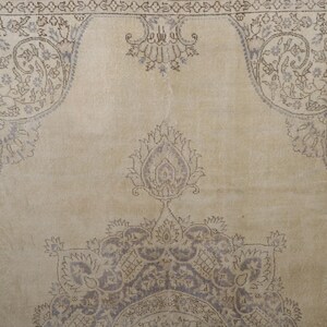 Puede incluir: Una alfombra beige con intrincados dise&ntilde;os florales y de cachemira en tonos grises y marrones. La alfombra presenta un dise&ntilde;o de medall&oacute;n central y bordes ornamentados, creando una est&eacute;tica vintage.