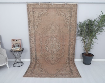 May include: A vintage-style rug with a beige background and intricate floral patterns in a darker brown shade. The rug has a faded, distressed look, giving it a rustic and antique feel.