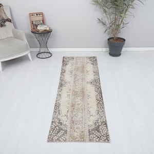 May include: A beige and brown patterned runner rug with a floral design. The rug is approximately 2.5 feet wide and 8 feet long.