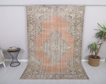 May include: A vintage rug with a peach-colored background and a detailed floral pattern in shades of beige, brown, and gray. The rug has a distressed look and is perfect for adding a touch of bohemian style to any room.