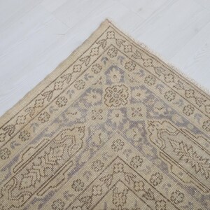 Puede incluir: Vista a&eacute;rea de una alfombra beige y gris estampada. La alfombra presenta un dise&ntilde;o central de medall&oacute;n y un borde con motivos florales y geom&eacute;tricos. Se coloca sobre una superficie blanca.