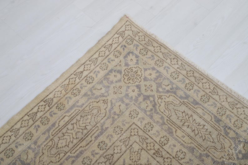 Puede incluir: Vista a&eacute;rea de una alfombra beige y gris estampada. La alfombra presenta un dise&ntilde;o central de medall&oacute;n y un borde con motivos florales y geom&eacute;tricos. Se coloca sobre una superficie blanca.
