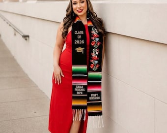 May include: A woman in a red dress and black graduation cap, wearing a graduation stole with the text "CLASS OF 2026", a mortarboard graphic, and the words "ERICA FIGUEROA MPH" and "FIRST GENERATION". The stole has a colorful striped design with floral embroidery.