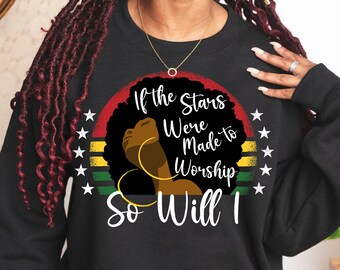 Puede incluir: Sudadera negra con un estampado gráfico de la cara de una mujer con un peinado afro. El gráfico incluye una puesta de sol con una franja roja, amarilla y verde y el texto "Si las estrellas fueron hechas para adorar, yo también lo haré."