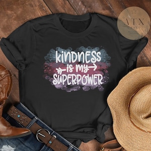 May include: Black t-shirt with a watercolor design featuring the text "kindness is my superpower" in white.