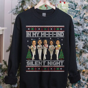 May include: Black Christmas sweater with a festive design featuring five cartoon men wearing white suits and holding gifts. The sweater has the text "In My Mi-i-ind Silent Night" printed on it.