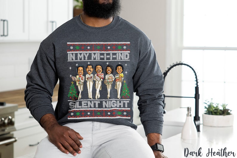 May include: A dark heather grey sweatshirt with a Christmas-themed design featuring a group of cartoon characters holding gifts. The text on the sweatshirt reads "In My Mi-i-ind Silent Night".
