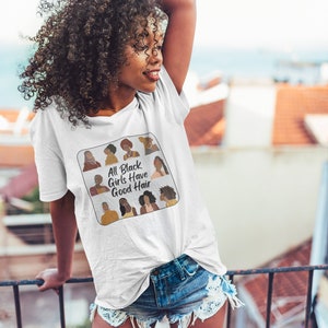 Peut inclure: T-shirt blanc avec un graphique d'un carr&eacute; avec le texte "All Black Girls Have Good Hair" et des illustrations de femmes noires avec diff&eacute;rentes coiffures.