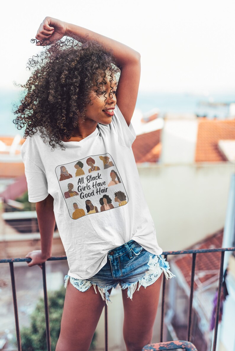 Peut inclure: T-shirt blanc avec un graphique d'un carr&eacute; avec le texte "All Black Girls Have Good Hair" et des illustrations de femmes noires avec diff&eacute;rentes coiffures.