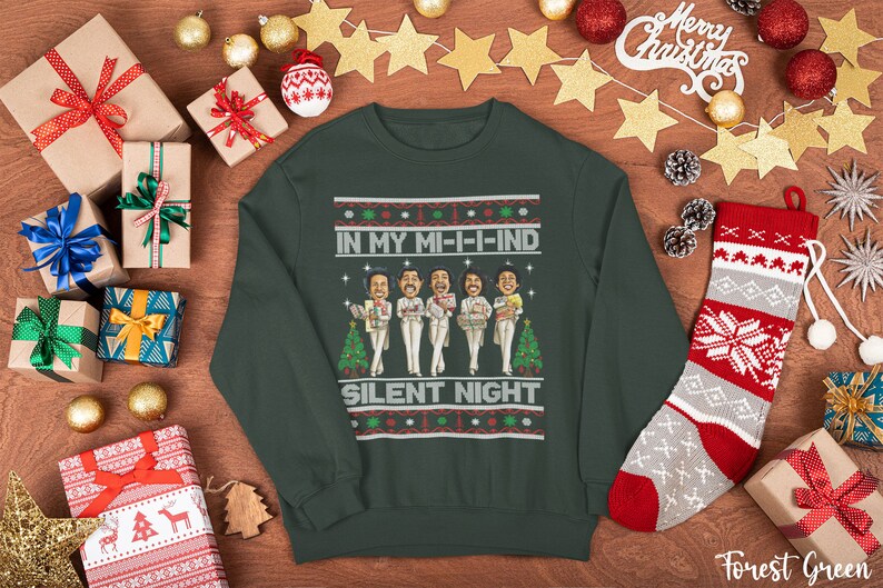 May include: A forest green Christmas sweater with a festive design featuring a group of cartoon figures singing "In My Mi-I-I-Ind Silent Night".