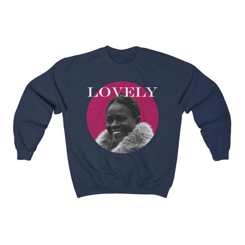 May include: Navy blue sweatshirt with a pink circle and the word "LOVELY" in white text. Inside the circle is a black and white photo of a woman with a fur collar.