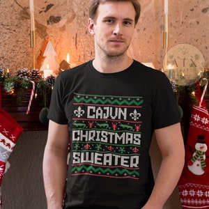 May include: A black t-shirt with a green and red Christmas-themed design that says "Cajun Christmas Sweater".