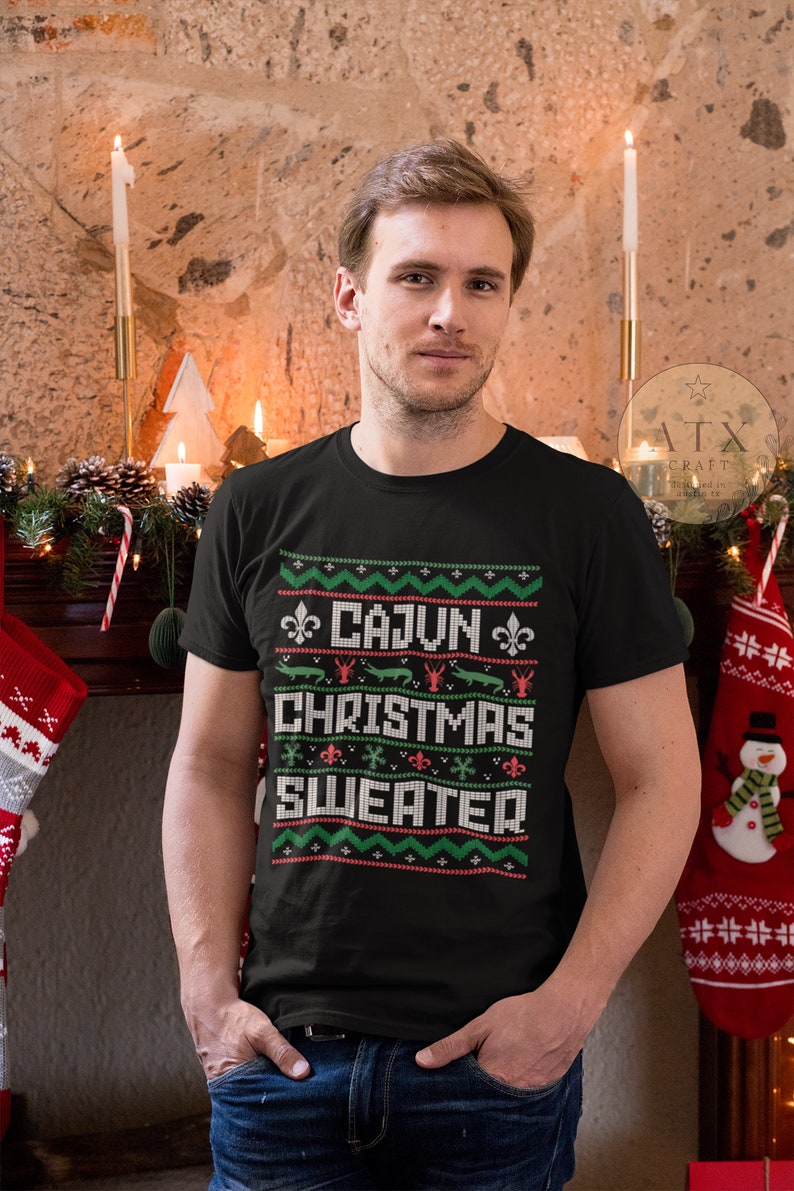 May include: A black t-shirt with a green and red Christmas-themed design that says "Cajun Christmas Sweater".