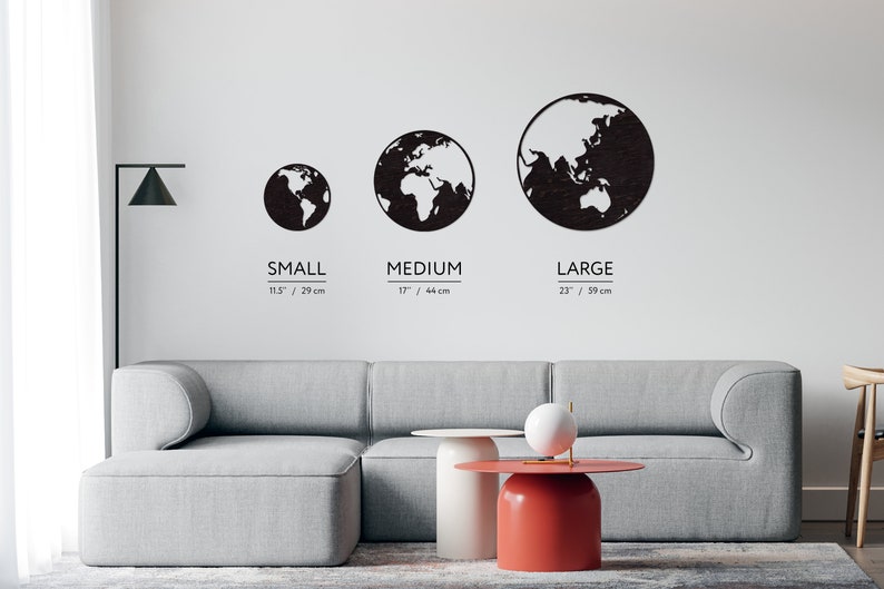 May include: Three black wooden world map wall decor pieces in different sizes: small (11.5 inches / 29 cm), medium (17 inches / 44 cm), and large (23 inches / 59 cm). The pieces are hanging on a white wall above a gray couch.