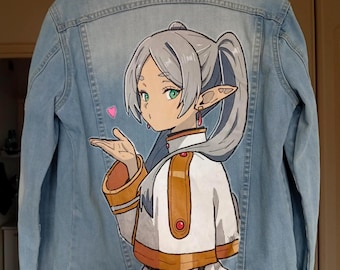 Könnte beinhalten: Hellblaue Jeansjacke mit handgemalter Illustration im Anime-Stil auf dem Rücken. Das Kunstwerk zeigt eine weibliche Figur mit silbernem Haar, grünen Augen und einem weißen und braunen Outfit. Ein rosa Herz schwebt in der Nähe ihrer Hand.