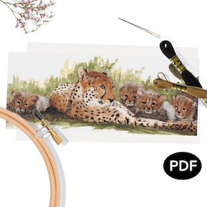 May include: A cross-stitch pattern featuring a cheetah and her cubs, with a wooden embroidery hoop, needles, and thread spools. The cheetah is brown with black spots, and the cubs are light brown. The pattern is labeled "PDF".