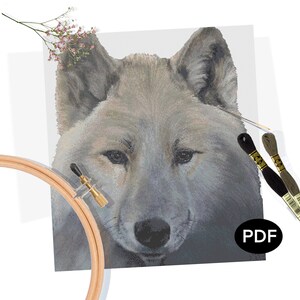 May include: A close-up of a cross-stitch pattern featuring a grey wolf with a white background. The pattern is on Aida cloth and includes a needle and floss.