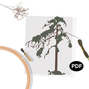 Può includere: Uno schema di punto croce con un albero verde stilizzato su sfondo bianco. Lo schema è stampato su un pezzo di stoffa bianca e include un ago e filo da ricamo.