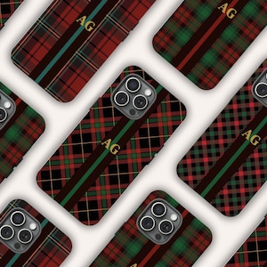 May include: Multiple smartphone cases featuring a red, green, and black plaid tartan pattern. Each case displays a vertical stripe with the gold-colored letters AG centered on the back. The cases include a circular cutout for a triple-lens camera.