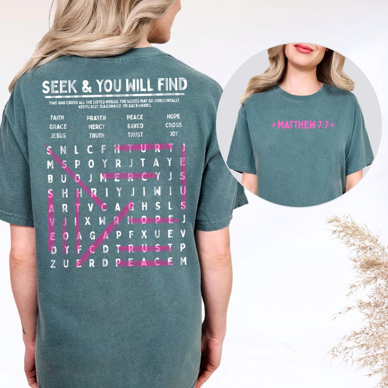 May include: A teal short-sleeve t-shirt featuring a word search puzzle on the back with the text SEEK & YOU WILL FIND and a list of words including FAITH, PRAYER, PEACE, and HOPE. The front of the shirt displays the pink text MATTHEW 7:7.