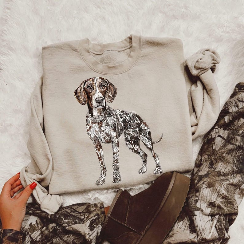May include: A beige sweatshirt with a graphic print of a brown and white German Shorthaired Pointer dog.