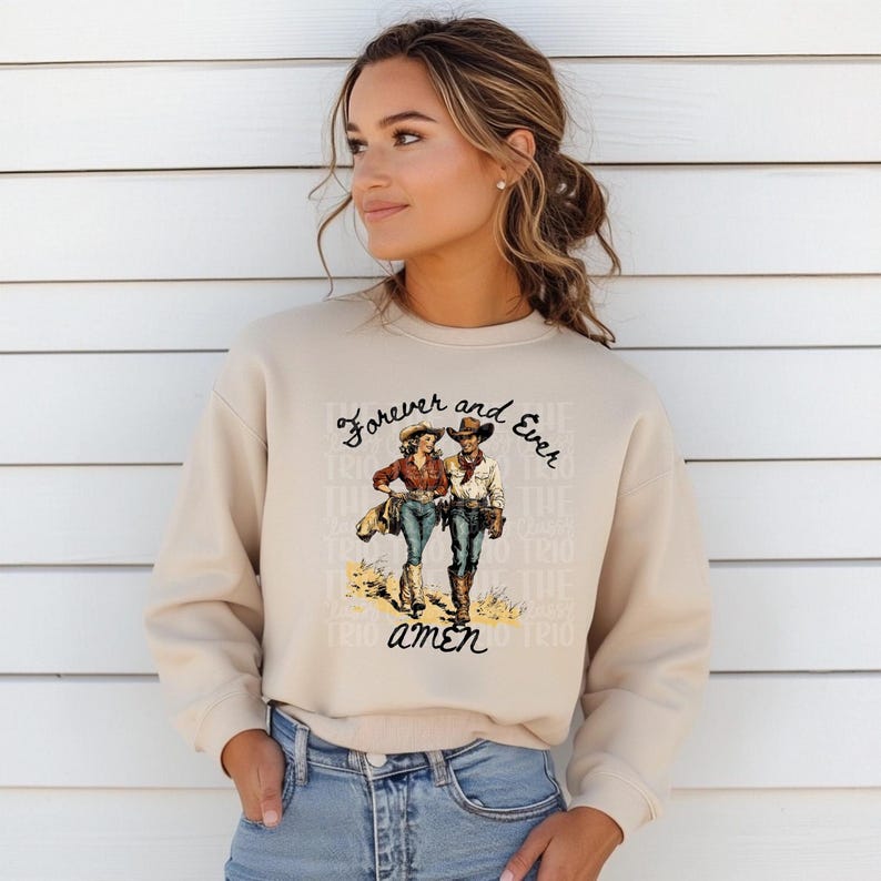 Puede incluir: Una sudadera beige con un estampado gr&aacute;fico de una pareja de vaqueros caminando. El texto en la sudadera dice "Forever and Ever Amen".