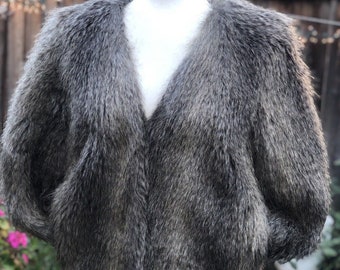 May include: A gray faux fur jacket with a v-neck and long sleeves.