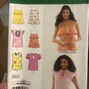 May include: A sewing pattern for a women's top with different neckline and sleeve options. The pattern includes five different styles: a sleeveless top with a ruffled neckline, a sleeveless top with a floral print, a top with a ruffled neckline and short sleeves, a top with a mandarin collar and short sleeves, and a top with a mandarin collar and short sleeves. The pattern is for sizes D5 4, 6, 8, 10, 12, EUR. 30-38, FR. 32-40. The pattern is from Simplicity.