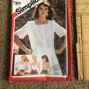 May include: Simplicity sewing pattern envelope, size 14, featuring a woman in a white blouse with lace trim. The envelope is red and white with the Simplicity logo and pattern number 5995. Includes images of other blouse styles.