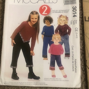 May include: McCall's sewing pattern number 3014 for a child's outfit. The pattern includes two pairs of pants and two tops. The pattern is for sizes 3, 4, and 5. The pattern is called "Hour Separates" and the instructions are in both English and French.
