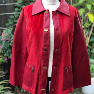 May include: A red leather jacket with a suede collar and gold-toned buttons. The jacket has two zippered pockets on the front.