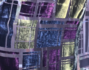 May include: A sheer fabric scarf with a geometric pattern of overlapping squares in shades of purple, green, and blue.