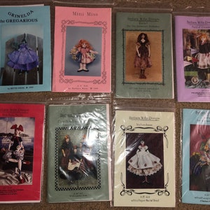 May include: A collection of eight doll-making patterns, featuring various designs and themes. The patterns are printed on paper and have colorful covers with images of dolls and accessories.