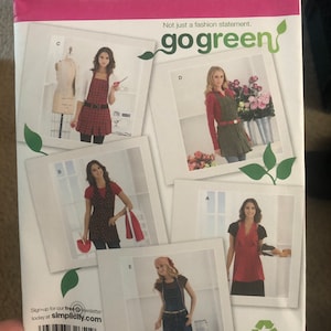 May include: A sewing pattern for five different styles of aprons. The pattern is called Simplicity 2682 and is for sizes S, M, L, and XL. The pattern is called "go green" and features a green leaf logo.