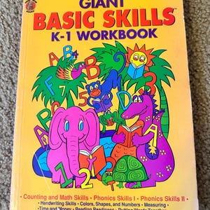 May include: A bright yellow K-1 workbook titled "GIANT BASIC SKILLS" with colorful illustrations of an elephant, a dragon, and other cartoon characters. The cover includes text about counting, phonics, and reading readiness.