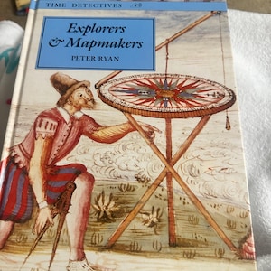 May include: A hardcover book titled Time Detectives: Explorers & Mapmakers by Peter Ryan. The cover features a historical illustration of a person in period clothing using a large compass and a tripod-mounted navigational instrument.