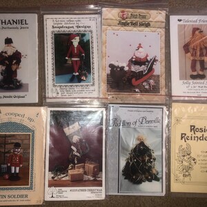 May include: A collection of eight Christmas craft patterns featuring various designs, including a Santa, a reindeer, a sleigh, a soldier, and a Christmas tree. The patterns are printed on white paper with colorful illustrations.