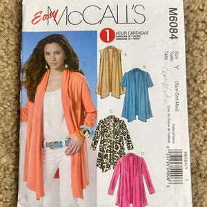 May include: McCall's M6084 sewing pattern for a one-hour cardigan. The pattern includes multiple cardigan styles in various colors and patterns, including solid tan, blue, animal print, and pink. The size is Y (Xsm-Sml-Med).