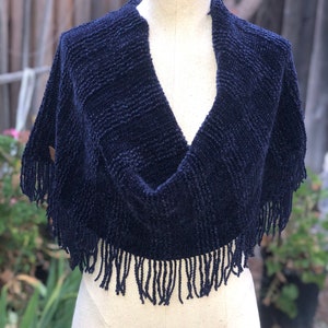 May include: A navy blue knitted shawl with fringe trim. The shawl is draped over a white mannequin.